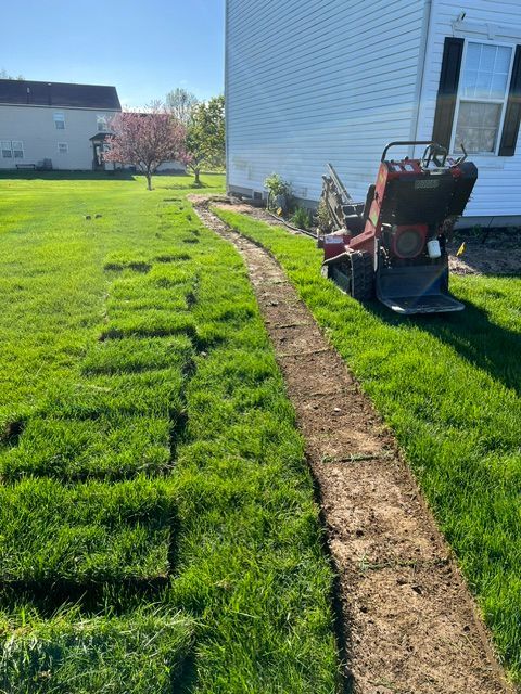 A lawn mower is sitting on top of a lush green lawn next to a house.