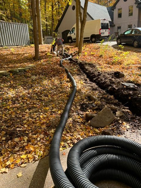 A black hose is laying on the ground in front of a house.