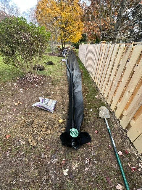 A hose is laying on the ground next to a wooden fence.