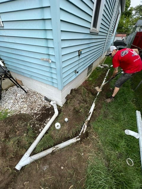 A man is digging a hole in the ground in front of a house.