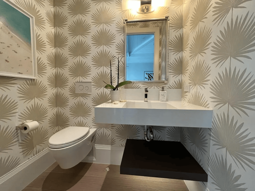 Small modern bathroom with patterned wallpaper, wall-mounted sink and toilet, mirror, and window.