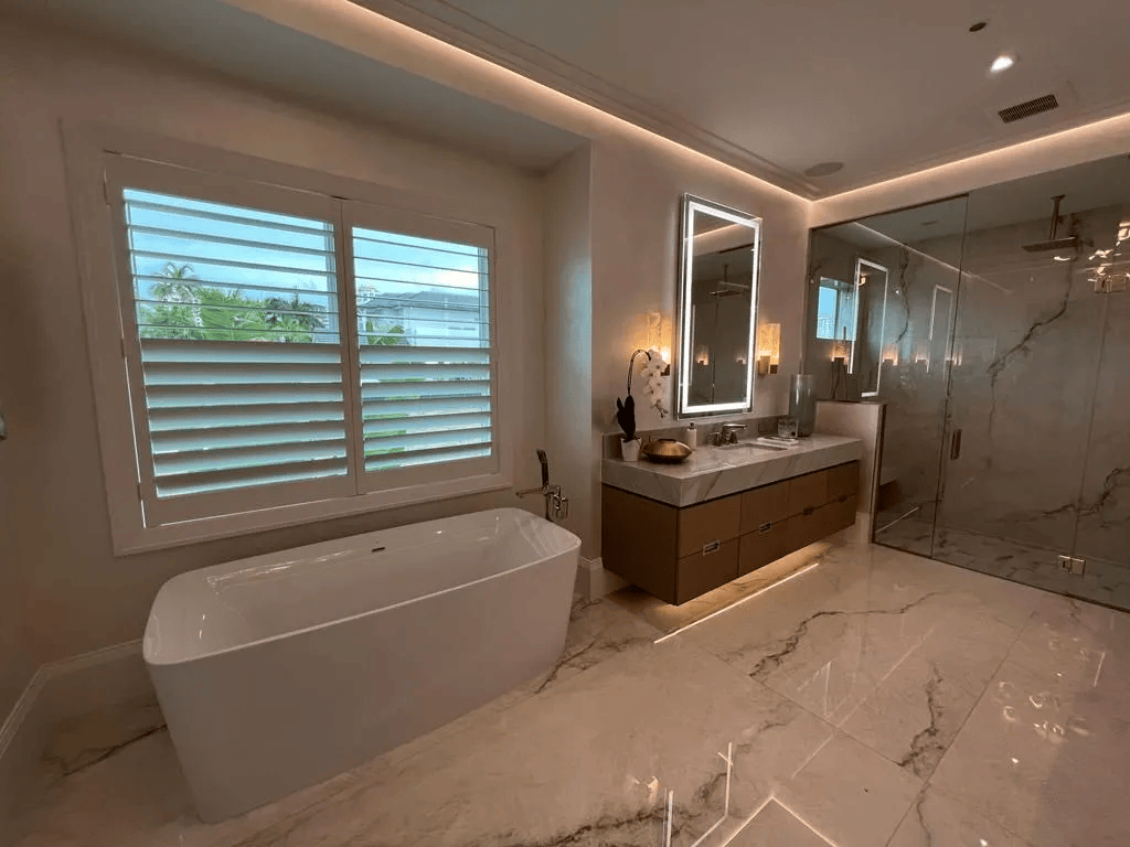 Modern bathroom with freestanding tub, double vanity, large mirror, marble finishes, and glass shower