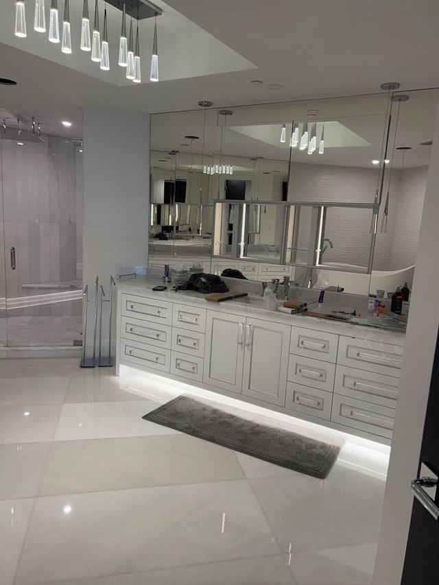 Bright white modern bathroom with double vanity, mirrors, sleek lighting, and large tile floor