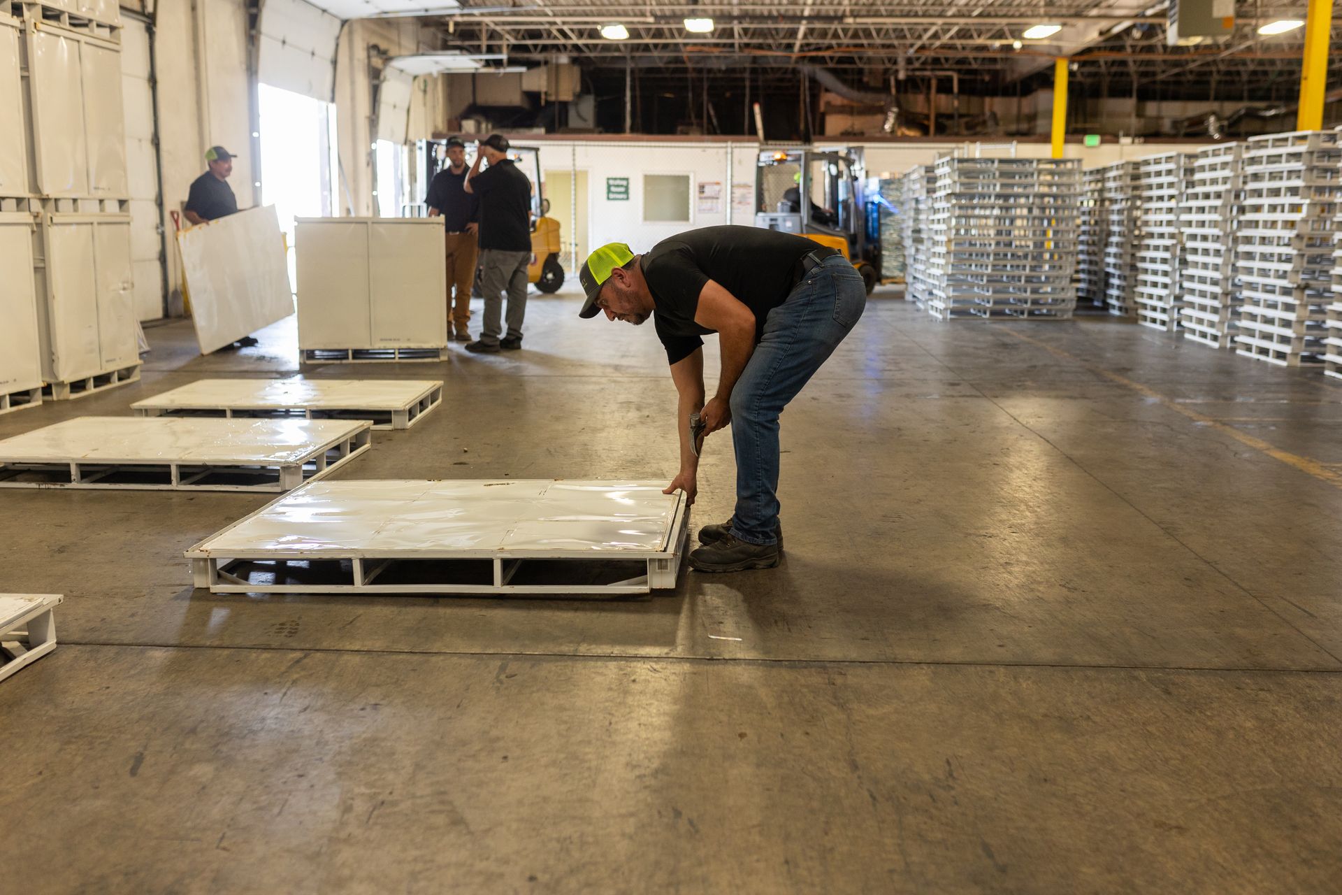 A man is measuring a pallet in a warehouse.