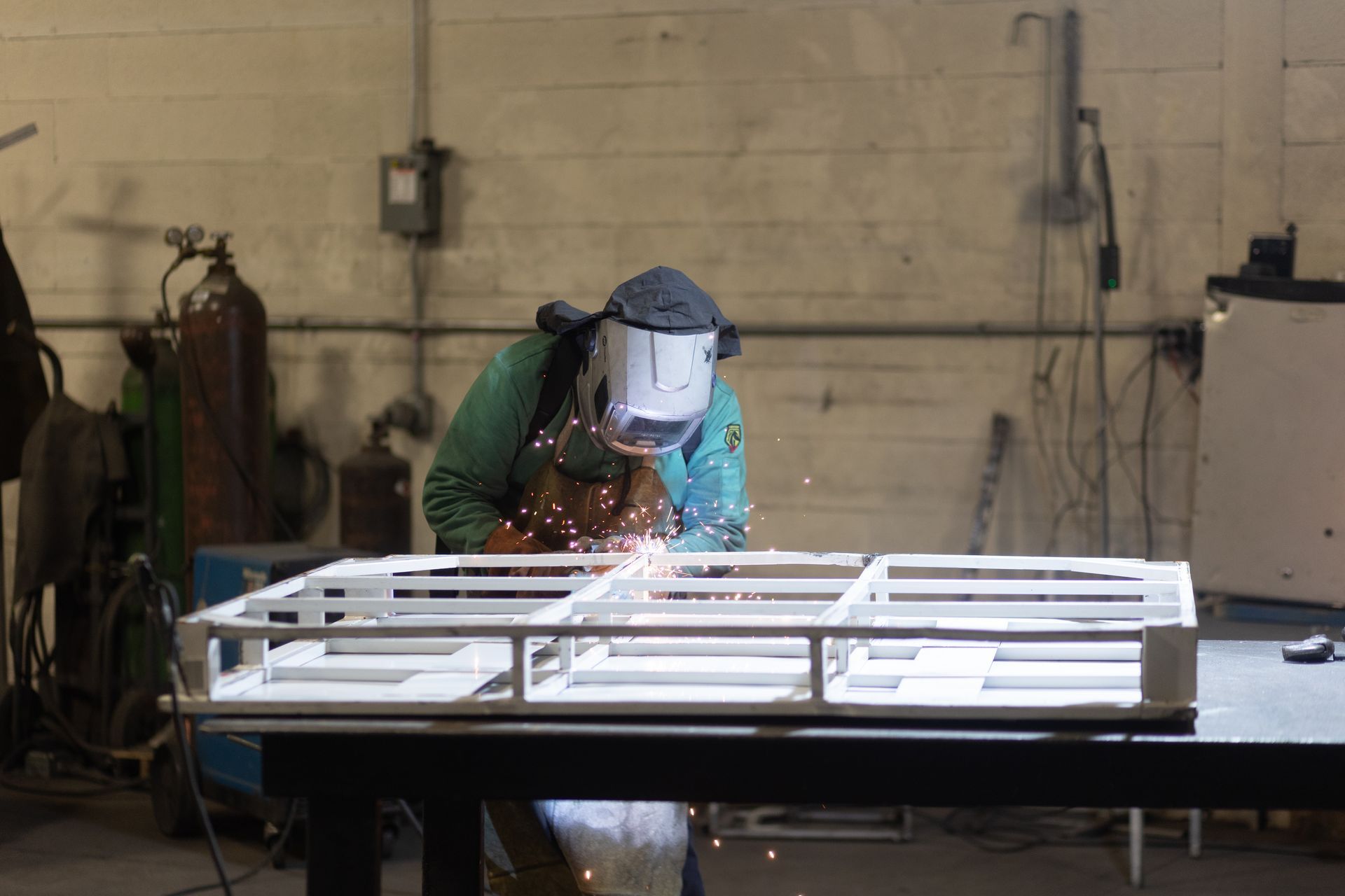 A man is welding a piece of metal in a factory.