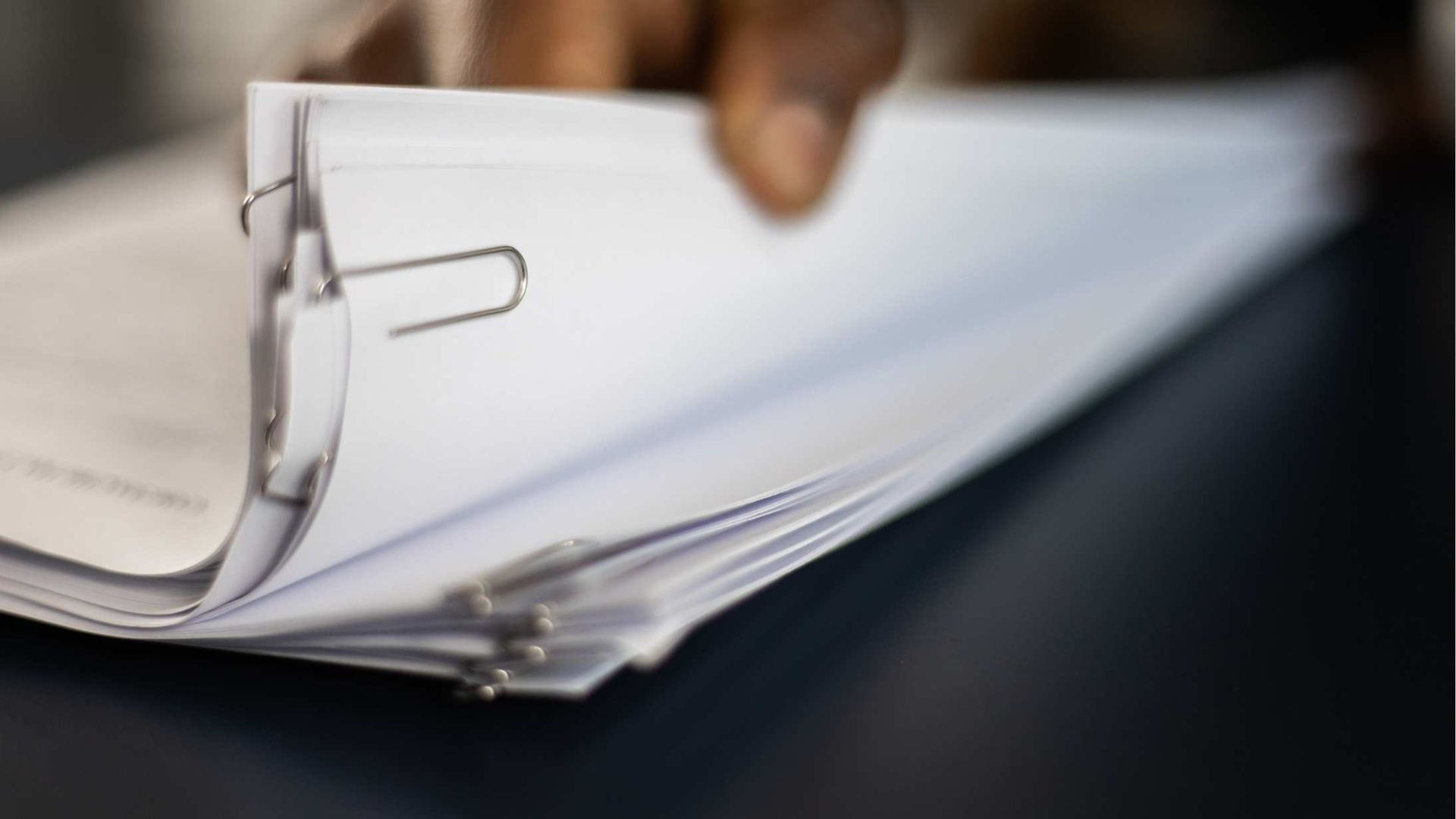 Close-up of a metal binder clip holding a stack of white papers