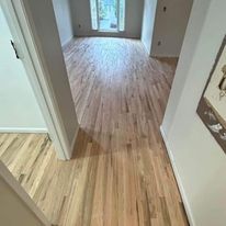 A hallway with hardwood floors leading to a living room.