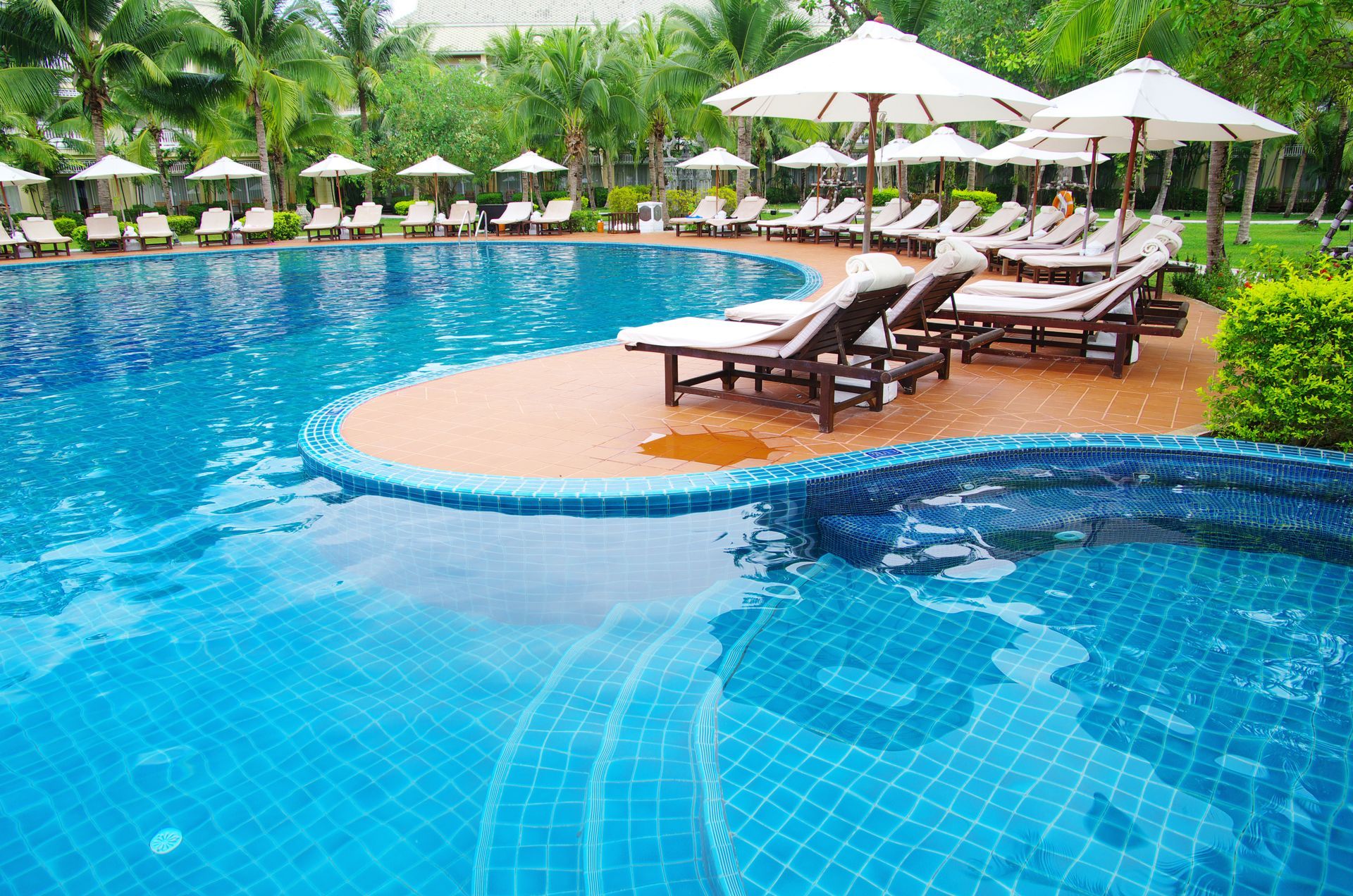 A large swimming pool surrounded by chairs and umbrellas.
