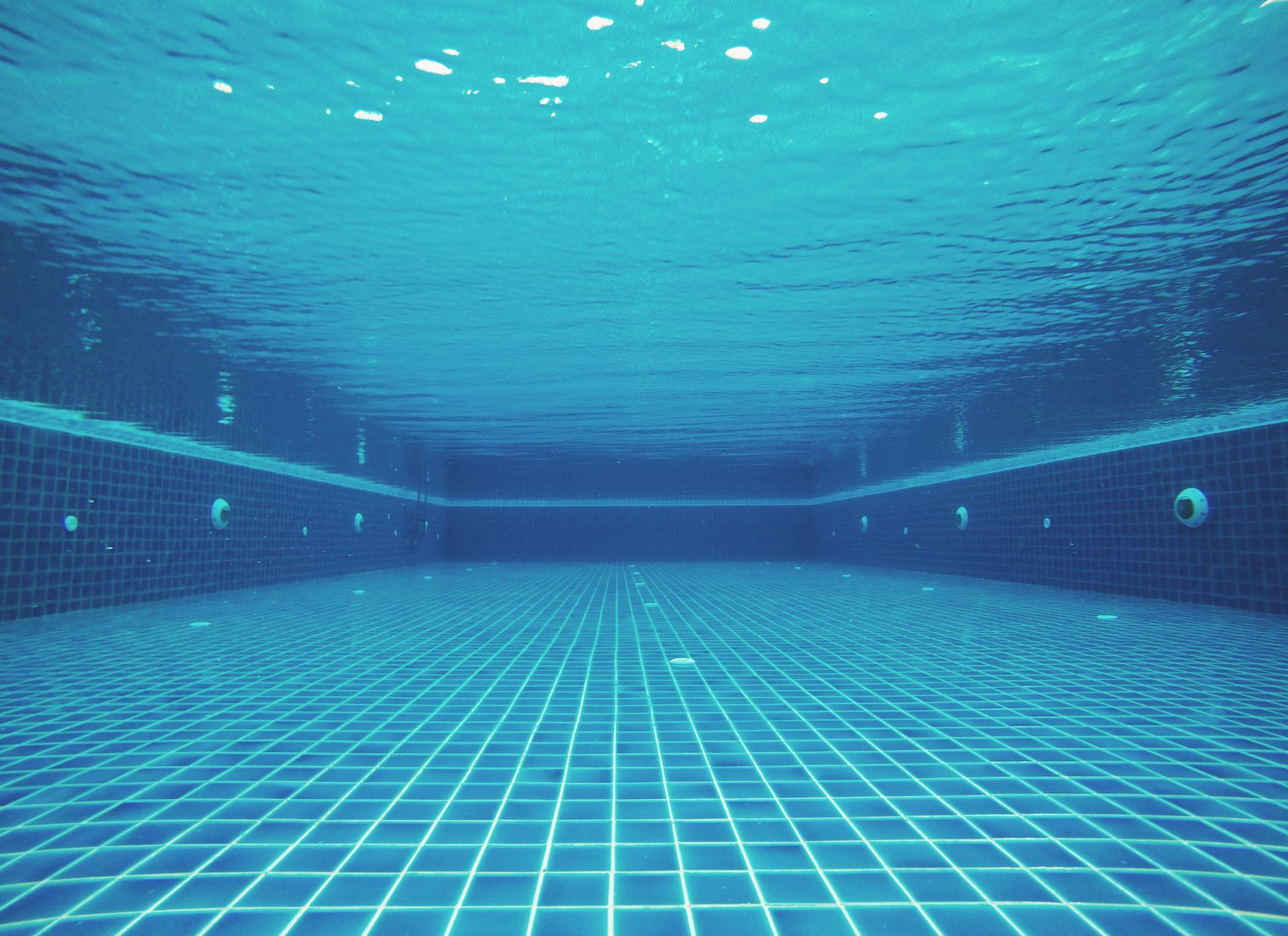 Underwater view of an empty swimming pool with blue tiles.