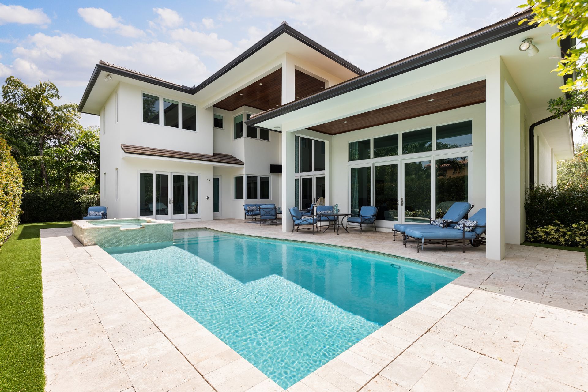 Luxury home with a pool, outdoor seating, and white exterior.