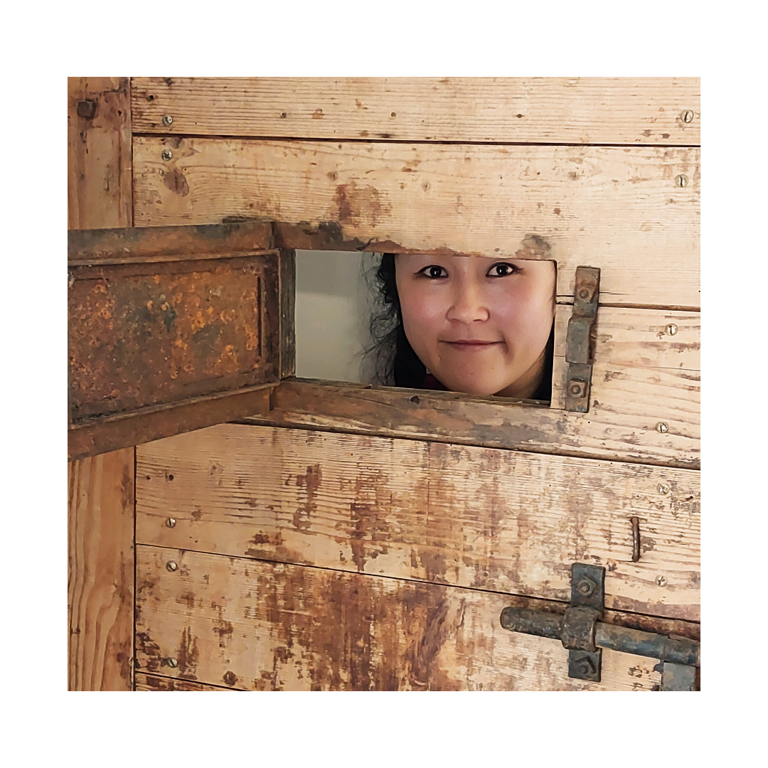 Eine Frau schaut aus einem Loch in einer Holztür