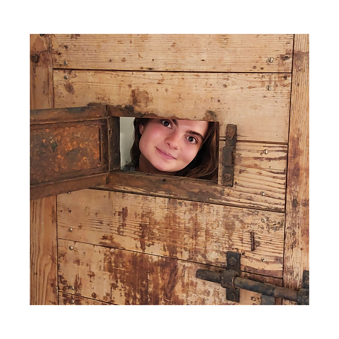 Eine Frau guckt aus einem Loch in einer Holztür