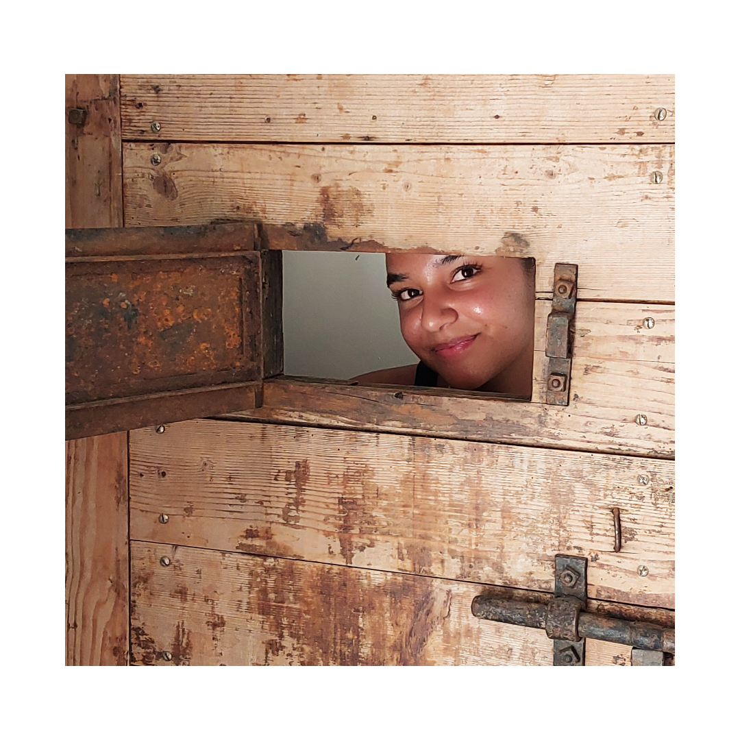 Eine Frau schaut aus einem Loch in einer Holztür
