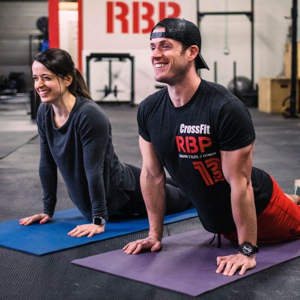 A man wearing a crossfit rbp shirt is stretching with a woman