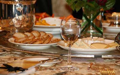 A table with plates of food and wine glasses on it.