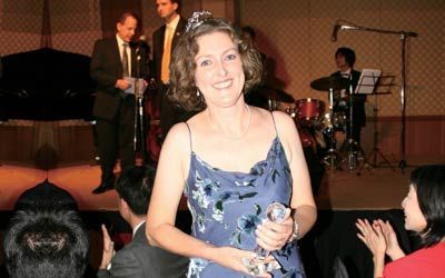 A woman in a blue dress is holding a trophy