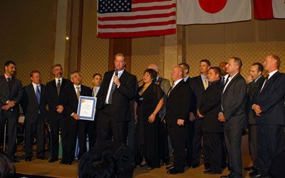 Boeing employees are standing in front of an American flag and a Japanese flag.