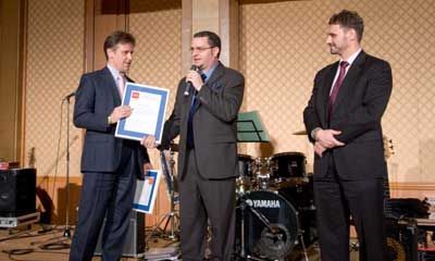 Three men in suits are standing in front of a Yamaha drum set.