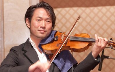 A man in a suit is playing a violin in front of a microphone.