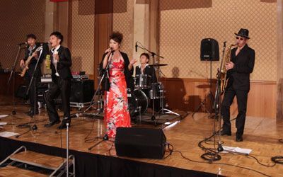 A group of people are standing on a stage playing instruments and singing into microphones.