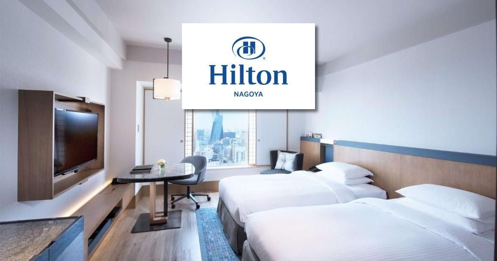 Hilton Nagoya hotel room interior with bed, desk, and TV; Hilton logo overlaid.