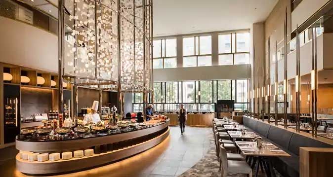 Elegant buffet restaurant interior with food stations, seating, and a decorative light fixture.