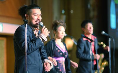 A group of people are singing into microphones on a stage.