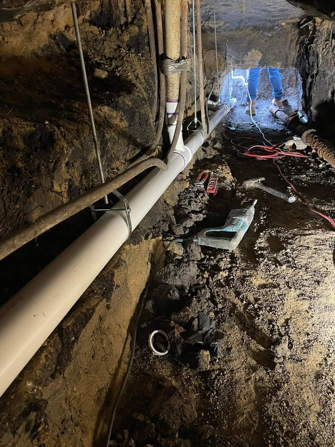 A person is working on a pipe in a basement.