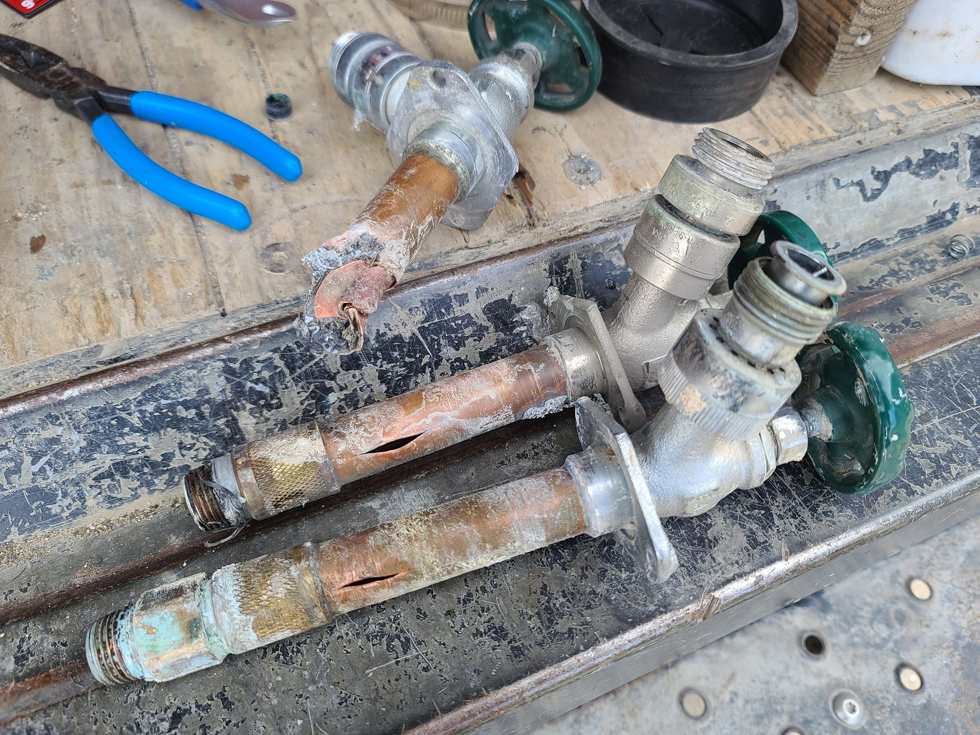A pair of faucets are sitting on a table next to a pair of pliers.