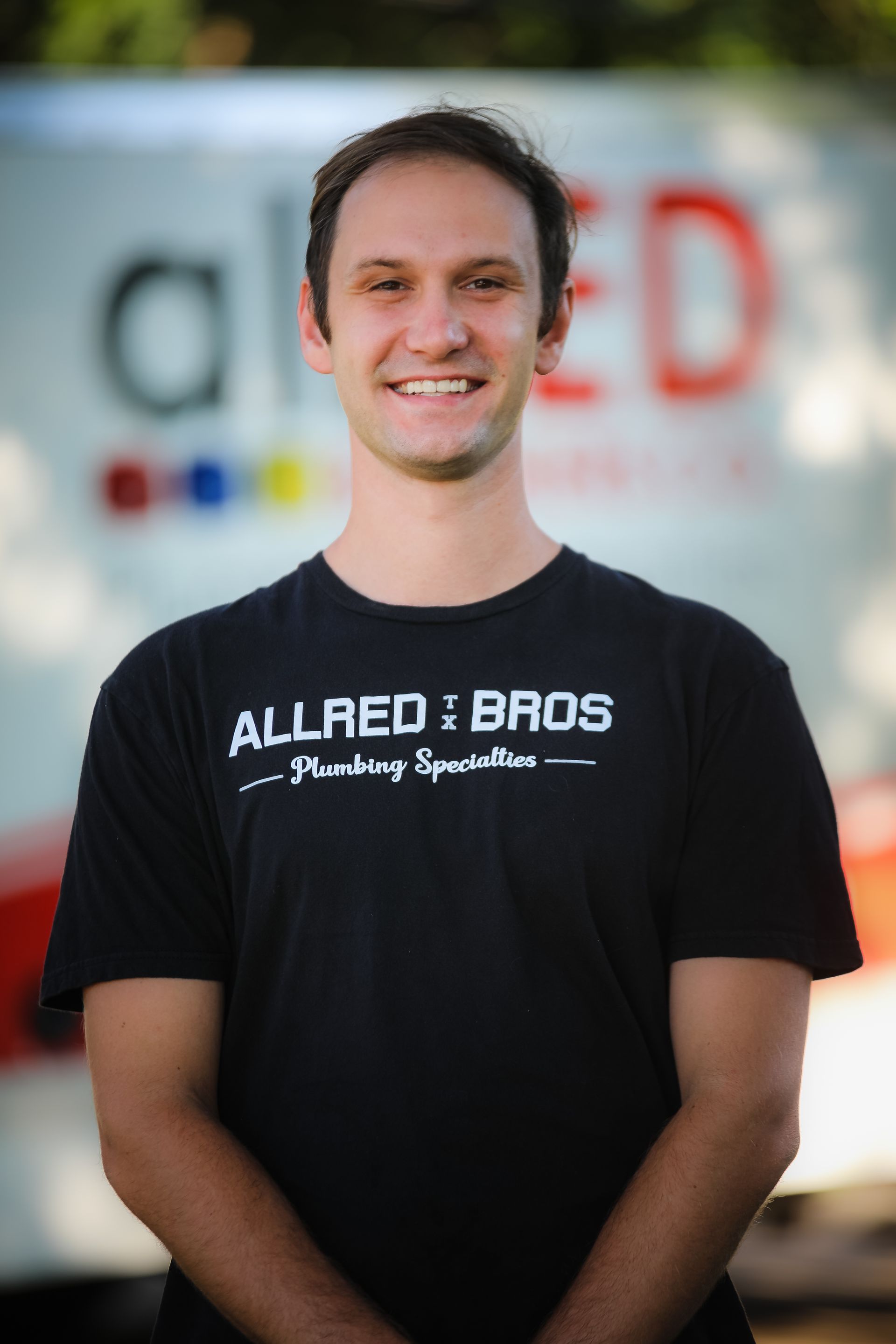 A man wearing a black shirt that says allred bros