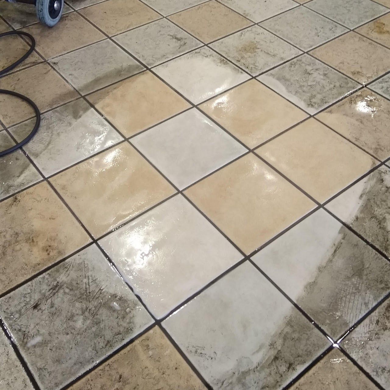 A dirty tile floor with a vacuum cleaner in the background