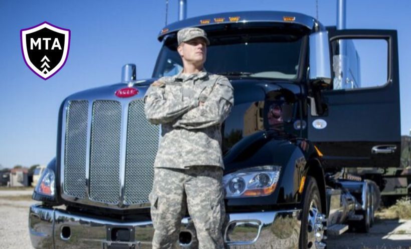 a soldier is standing in front of a truck with his arms crossed
