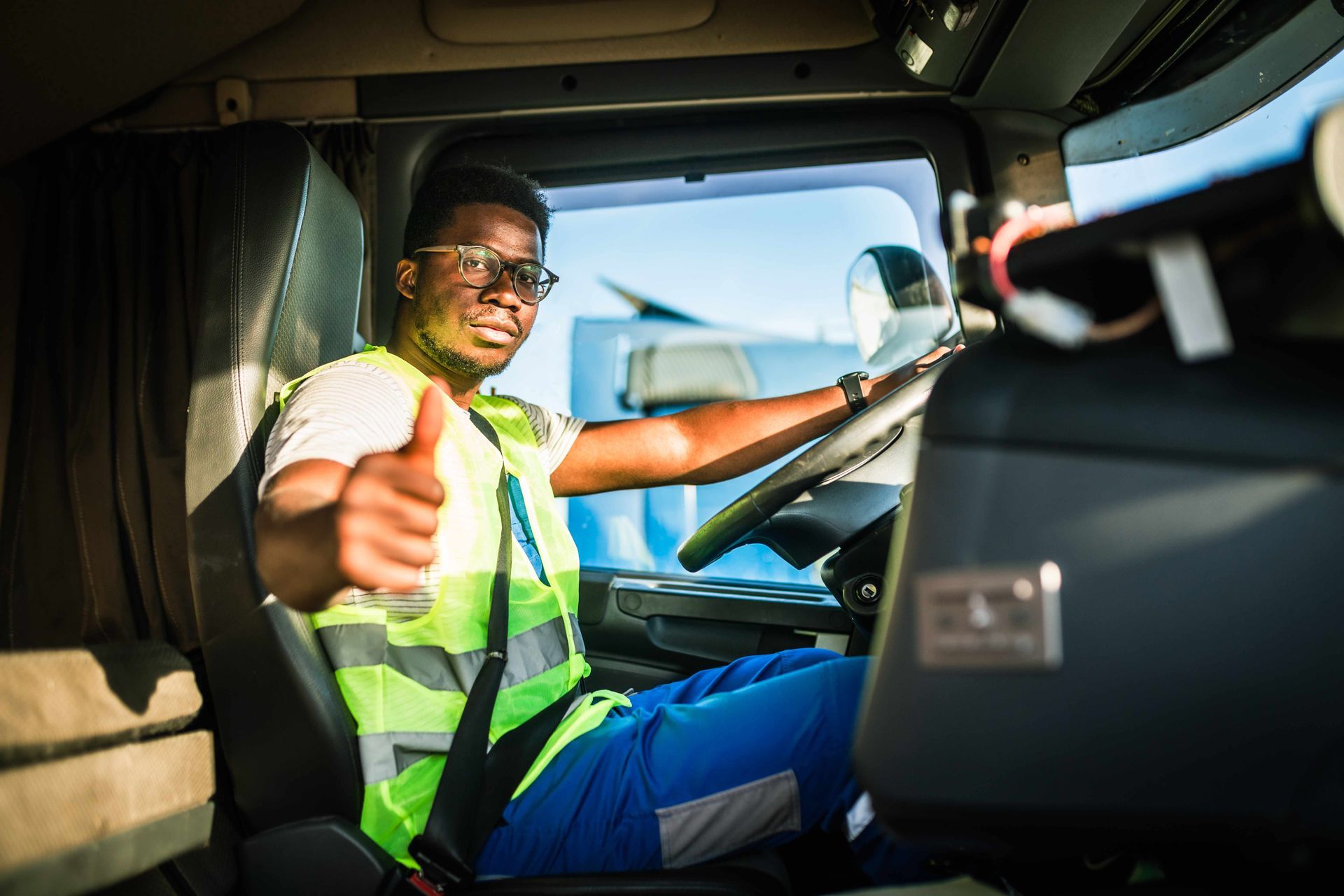 a man is sitting in the driver 's seat of a truck and giving a thumbs up