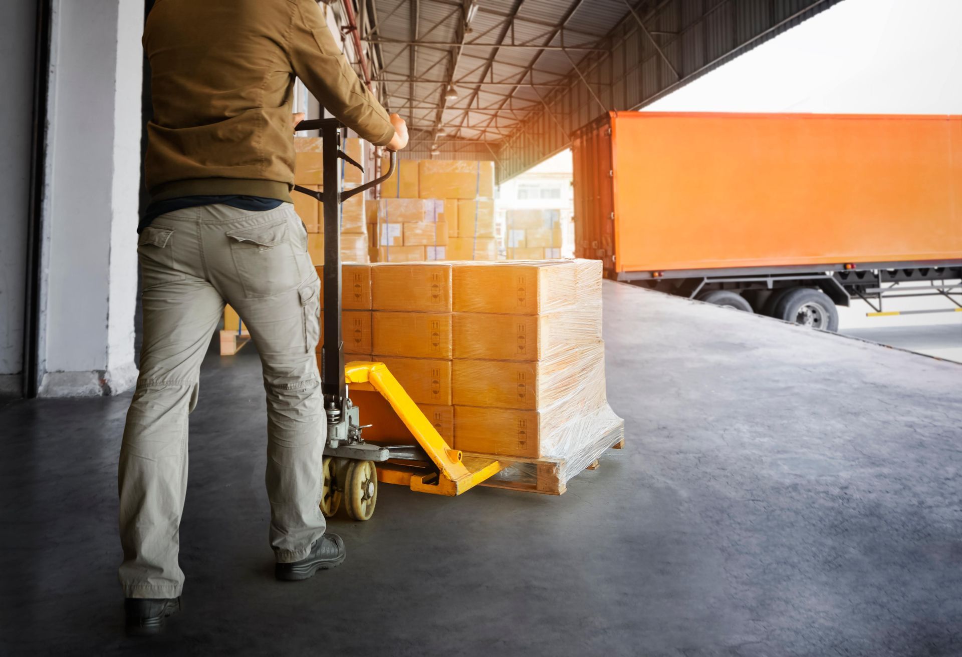 a man is pushing a pallet truck with boxes on it in a warehouse