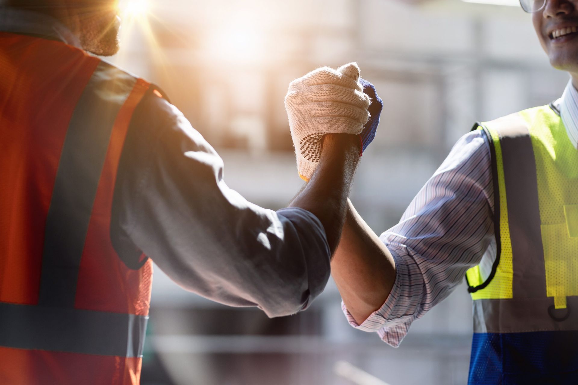 two construction workers are shaking hands in a factory