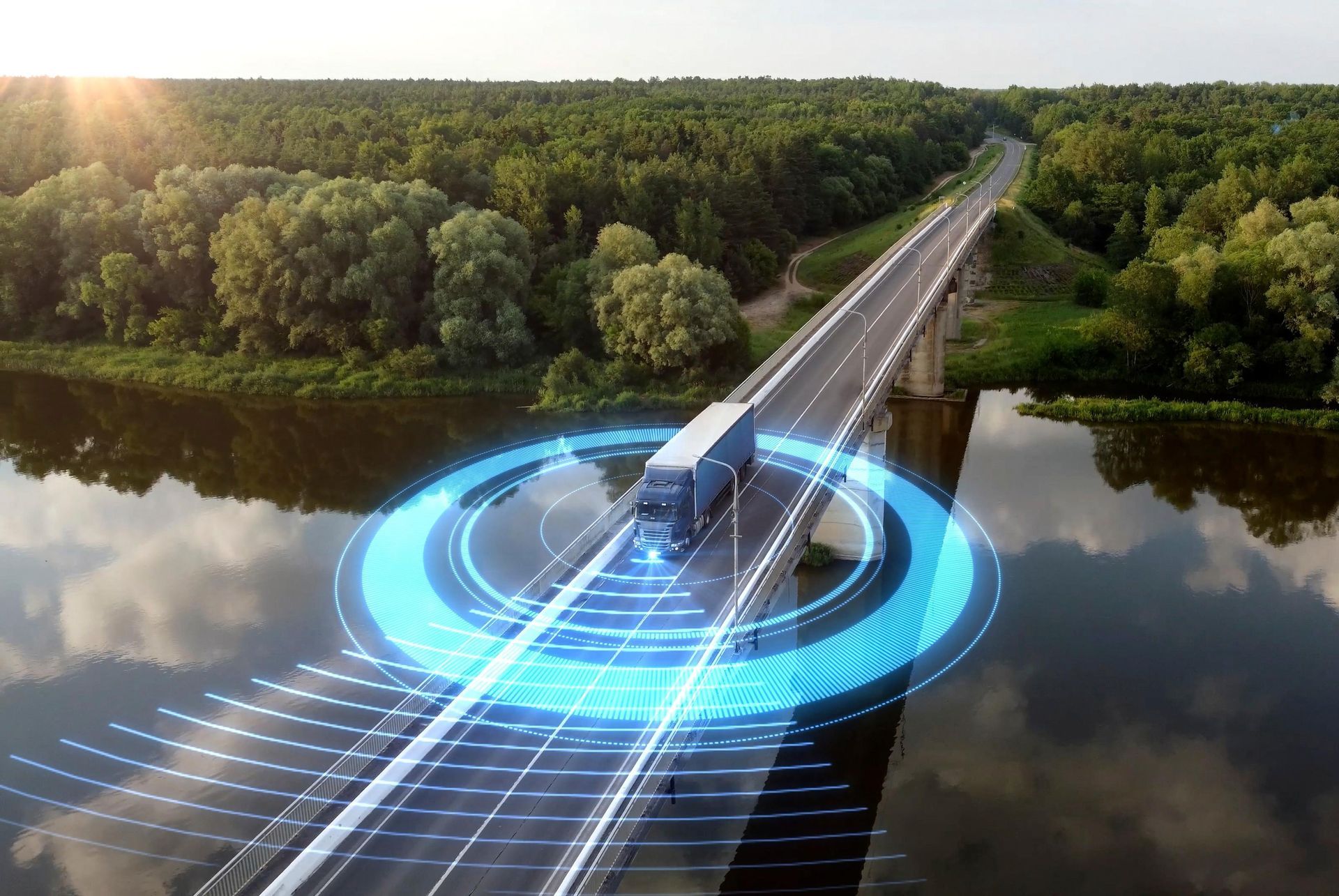 an aerial view of a truck driving on a highway next to a river