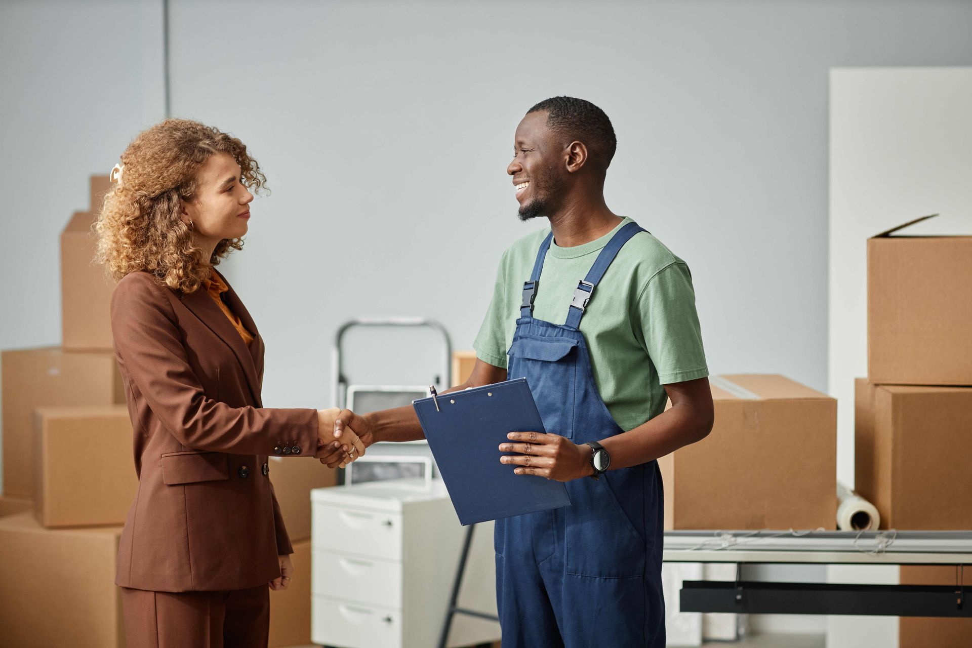 a man in overalls is shaking hands with a woman in a suit