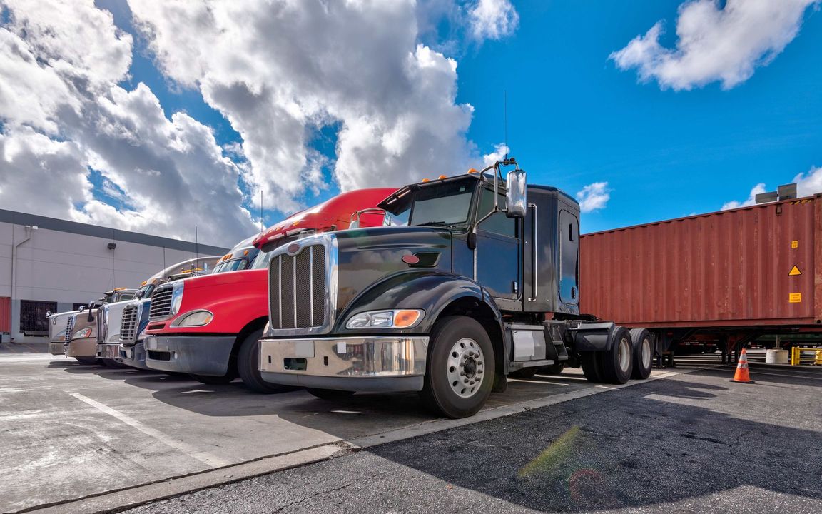 a row of semi trucks parked next to each other in a parking lot