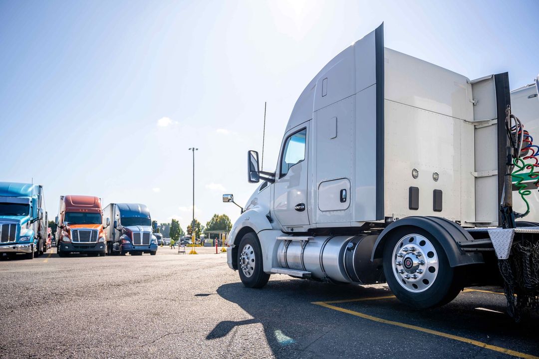 a row of semi trucks are parked in a parking lot