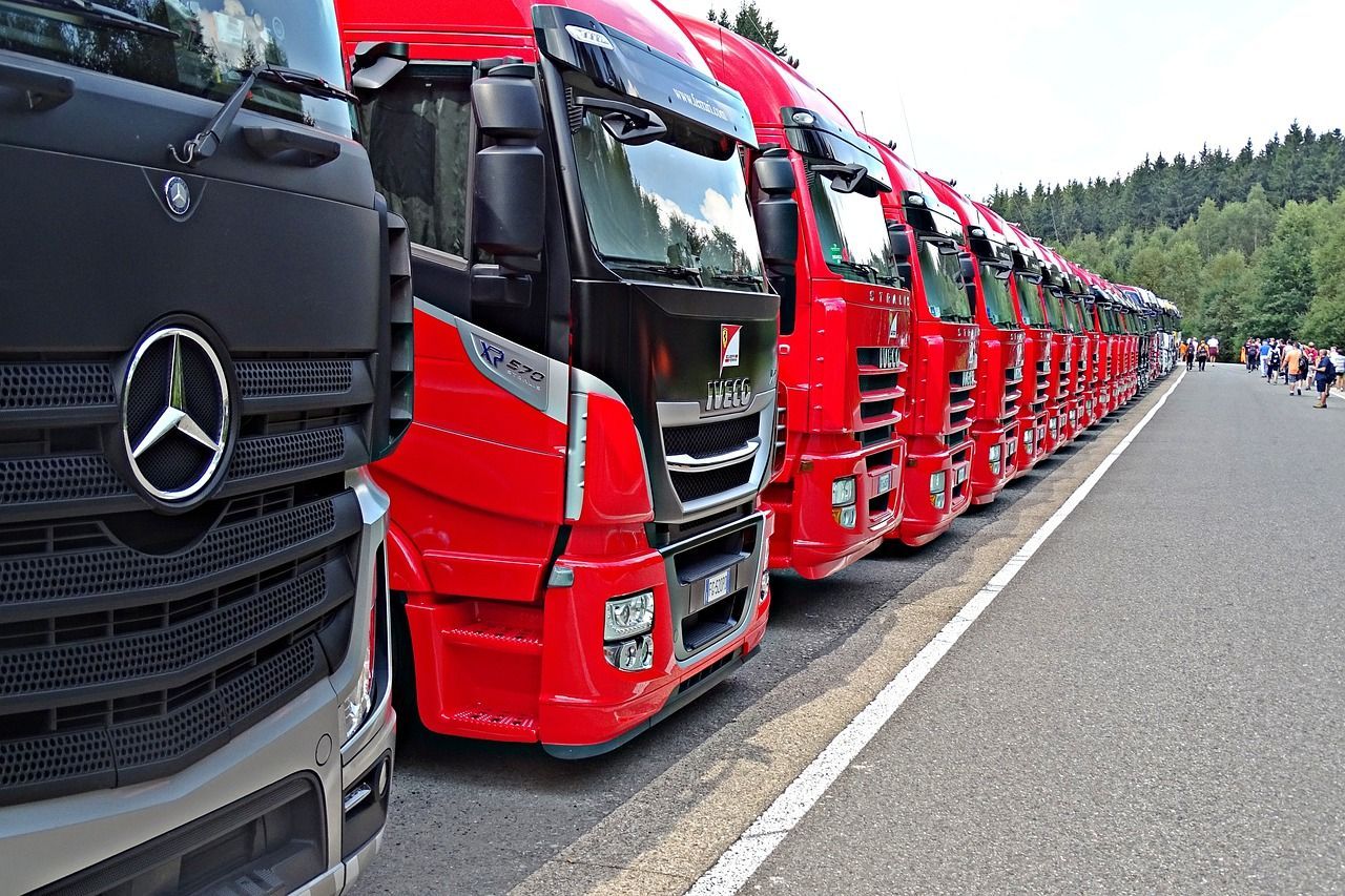 a row of red and black trucks are parked on the side of the road