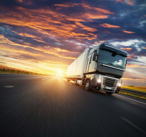 a semi truck is driving down a highway at sunset