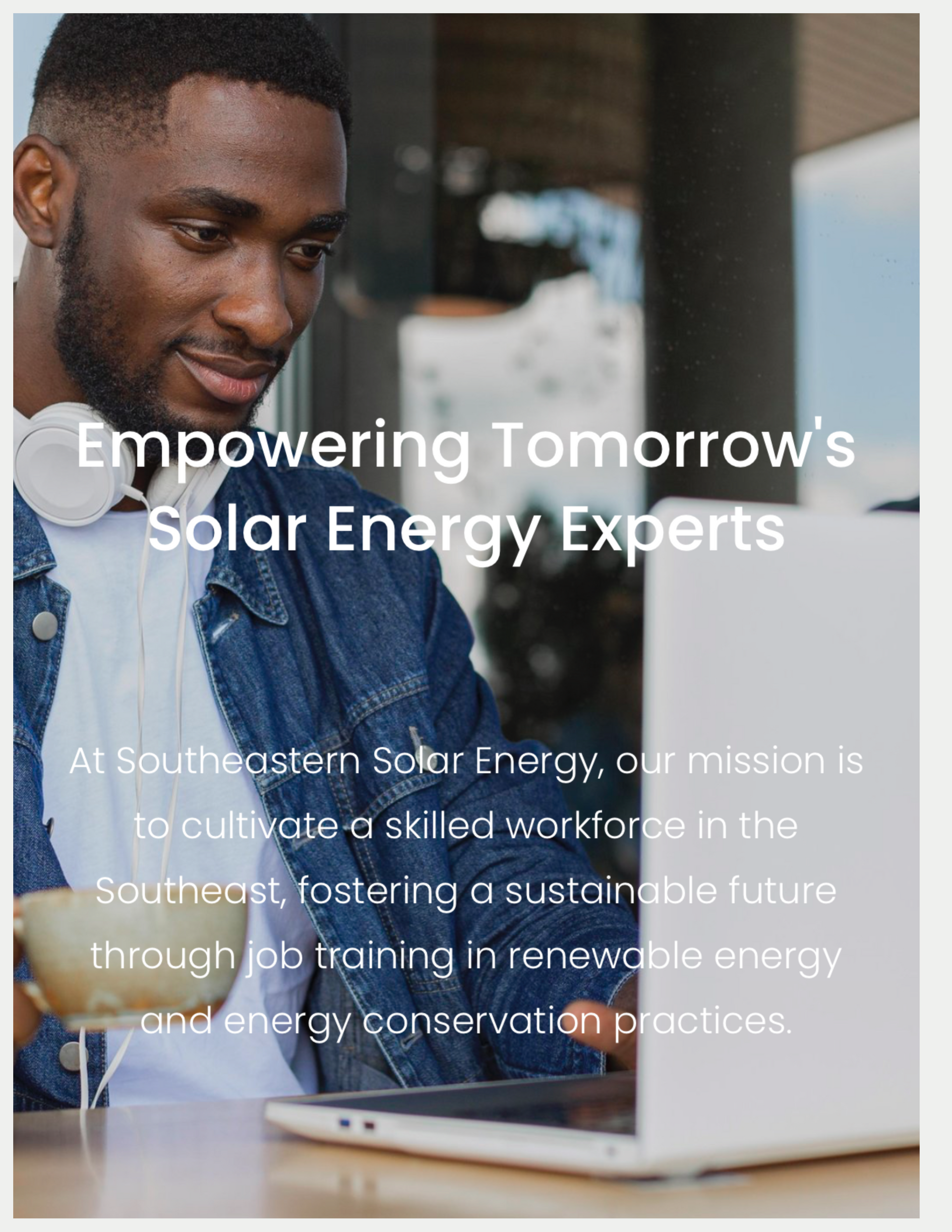 A man is sitting at a table using a laptop computer.