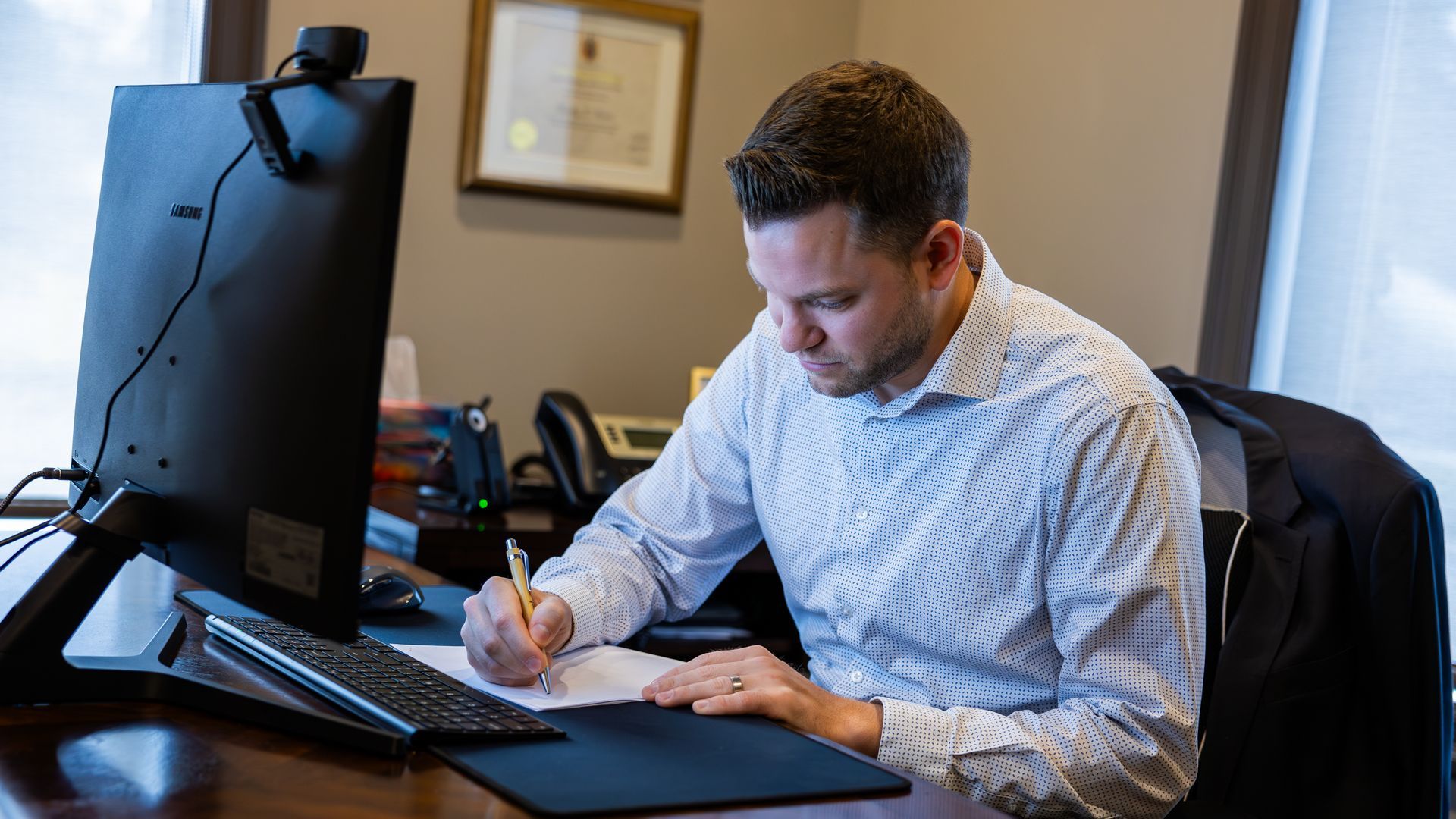 A professional focused on writing notes at his desk, representing the detailed planning work of a chartered financial planner in Salford.