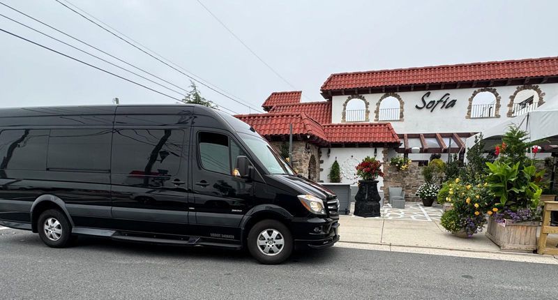 A black van is parked in front of a restaurant.