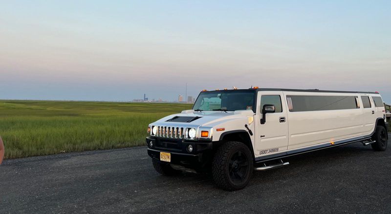A white hummer limousine is parked on the side of the road.