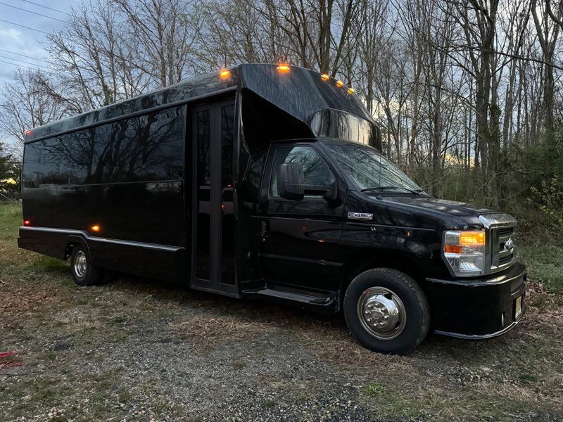 A black shuttle bus is parked in a gravel lot.