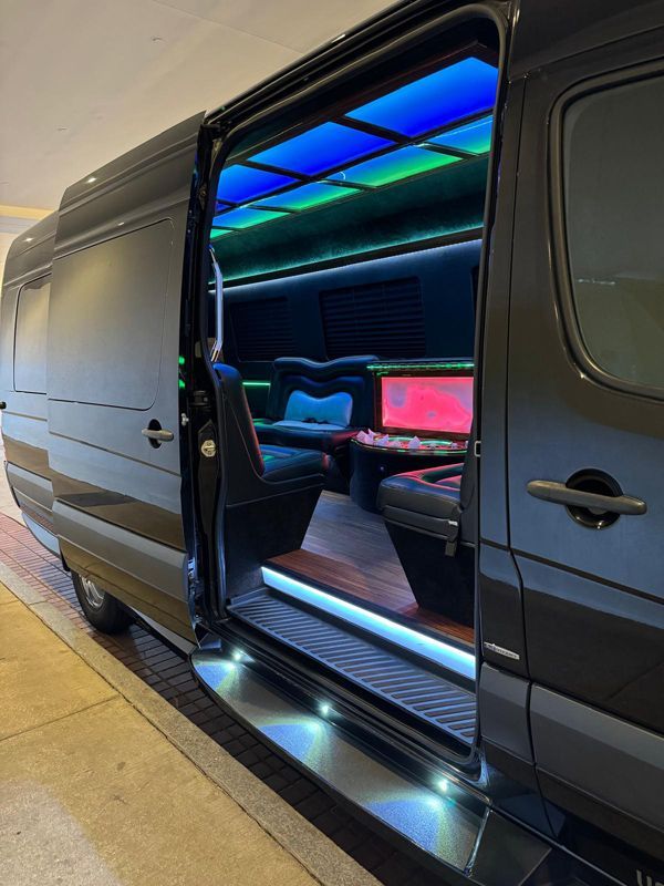 A black van with the door open is parked in a garage.