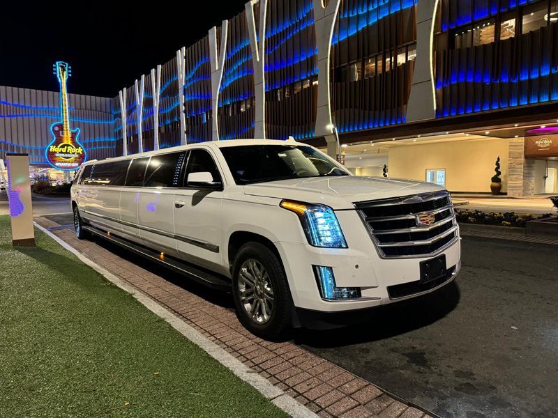 A white limousine is parked in front of a building at night.