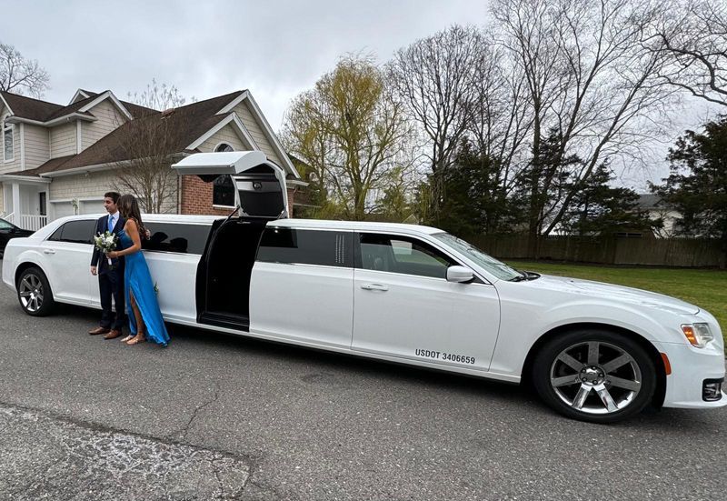 A couple of people standing next to a white limousine.