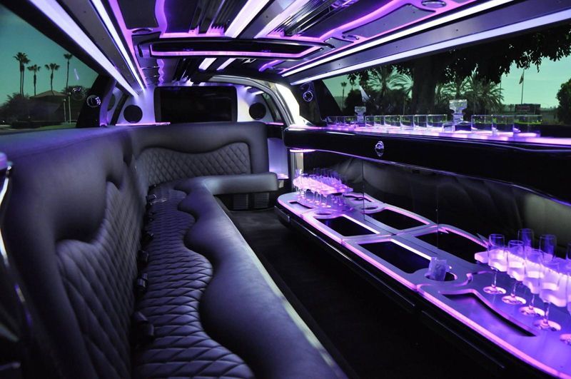 The inside of a limousine with purple lights on the ceiling.
